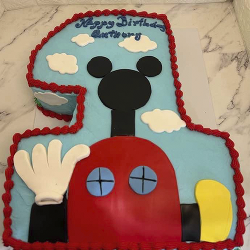 A pull-apart cake shaped like Mickeys house, decorated with green frosting and festive sprinkles.